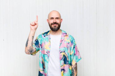 Kel adam neşeyle ve mutlulukla gülümsüyor, tek eliyle yukarıyı göstererek boşluğu kopyalıyor.