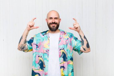 Kel bir adam kendi gülüşünü çiziyor, iki eliyle, olumlu ve mutlu görünüyor, sağIık kavramı.