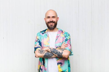 Kel adam mutlu, gururlu ve tatmin olmuş görünüyor. Kollarını kavuşturup gülümsüyor.