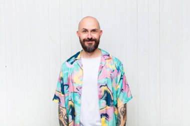 Kel adam pozitif ve kendinden emin gülümsüyor. Tatmin olmuş, arkadaş canlısı ve mutlu görünüyor.