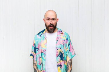 Kel adam şok olmuş, kızgın, sinirli ya da hayal kırıklığına uğramış, ağzı açık ve öfkeli görünüyor.