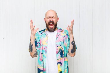 Kel adam öfkeyle bağırıyor, stresli ve elleri havada neden ben diye bağırıyor.