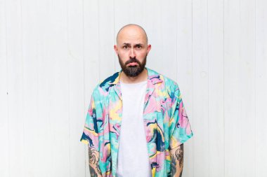 Kel bir adam üzgün ve mızmızlanıyor. Mutsuz bir bakışla, olumsuz ve hayal kırıklığına uğramış bir tavırla ağlıyor.