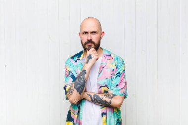 Kel adam ciddi görünüyor, kafası karışık, kararsız ve düşünceli, seçenekler ve tercihler arasında şüpheci