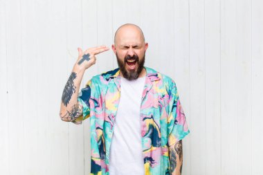 Kel adam mutsuz ve stresli görünüyor, intihar jesti elle silah işareti yapıyor, kafasını işaret ediyor.