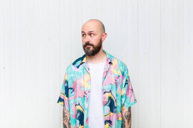 Kel adam merak ediyor, mutlu düşünceler ve fikirler düşünüyor, hayal kuruyor, kenarda yer arıyor.