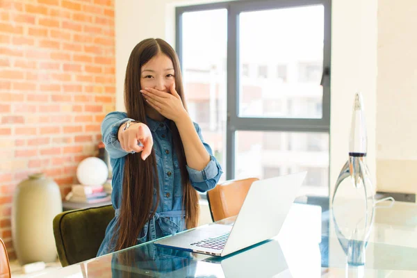 young asian woman laughing at you, pointing to camera and making fun of or mocking you