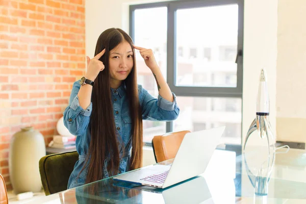 young asian woman with a serious and concentrated look, brainstorming and thinking about a challenging problem