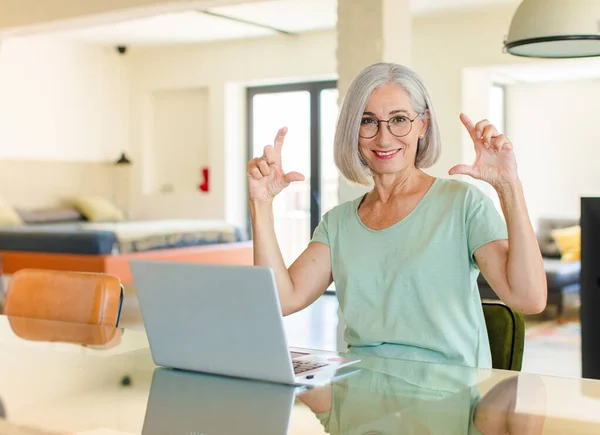 middle age woman framing or outlining own smile with both hands, looking positive and happy, wellness concept