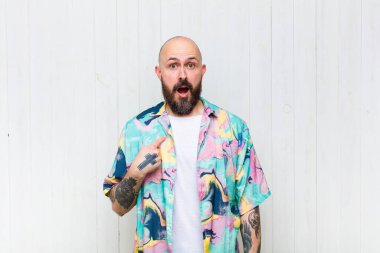 Şok olmuş ve ağzı açık, kendini işaret eden kel bir adam.