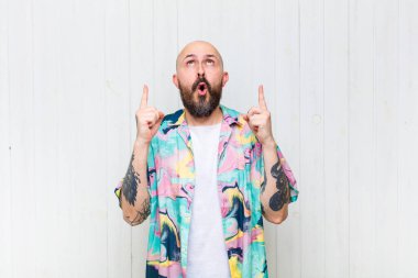 Kel adam korkuyla ve ağzı açık bir şekilde şaşkın ve şaşkın bir bakışla yukarıya bakıyor.