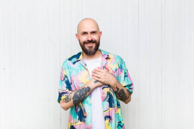 Kel adam romantik, mutlu ve aşık, neşeyle gülümseyen ve kalbe yakın el ele tutuşan