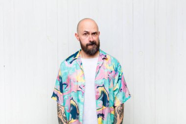 Kafası karışmış, kafası karışmış, sinirsel bir hareketle dudağını ısıran, sorunun cevabını bilmeyen kel bir adam.