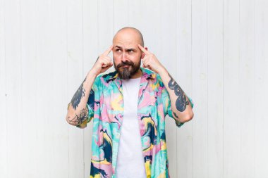 Kel adam odaklanmış ve bir fikir üzerinde kafa yoruyor, bir meydan okumaya ya da soruna bir çözüm hayal ediyor.