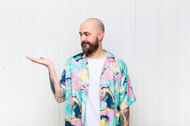 Kel adam kendini mutlu hisseder ve gelişigüzel gülümser. Elinde tuttuğu bir nesneye ya da konsepte bakar.