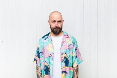 Kafası karışık ve şüpheli hisseden kel bir adam merak ediyor ya da karar vermeye çalışıyor.