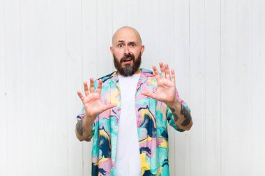 Kel adam sersemlemiş ve korkmuş hissediyor. Korkutucu bir şeyden korkuyor. Elleri açık ve uzak dur diyor.