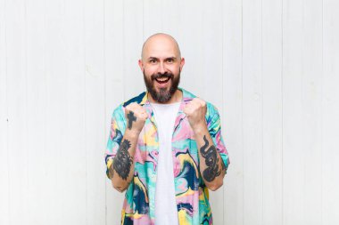 Kel adam zaferle bağırıyor, gülüyor, mutlu ve heyecanlı hissediyor ve başarıyı kutluyor.