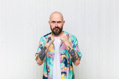 Kel adam kendinden emin, sinirli, güçlü ve agresif görünüyor. Yumrukları boks pozisyonunda dövüşmeye hazır.