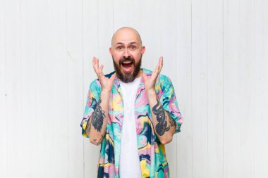 Kel bir adam beklenmedik bir sürprizden dolayı şaşkın, heyecanlı, gülen, şaşkın ve mutlu hissediyor.