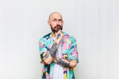 Kel düşünen, kuşkulu ve kafası karışık, farklı seçenekleri olan, hangi kararı vereceğini merak eden bir adam.