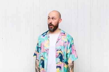 Kel adam şaşkın, mutlu, şaşkın ve şaşırmış hissediyor, ağzı açık bir şekilde yana bakıyor.