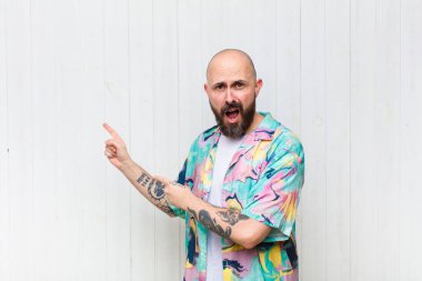 Kel adam şaşkın ve şaşırmış hissediyor. Kenardaki fotokopi alanını işaret ediyor. Şaşırmış, ağzı açık bir bakışla.