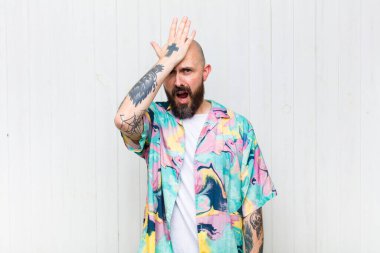 bald man raising palm to forehead thinking oops, after making a stupid mistake or remembering, feeling dumb