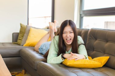 Genç Asyalı kadın agresif bir şekilde bağırıyor, çok kızgın, hayal kırıklığına uğramış, öfkeli ya da sinirli görünüyor, hayır diye bağırıyor