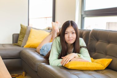 Asyalı genç bir kadın üzgün ve mızmızlanıyor, mutsuz bir bakışla, negatif ve hayal kırıklığına uğramış bir tavırla ağlıyor.