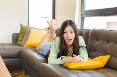 Genç Asyalı kadın korkmuş ve şok olmuş hissediyor, ağzı açık şaşkınlık içinde.