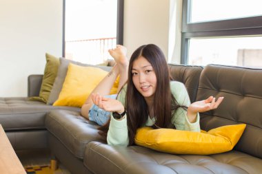 Genç Asyalı kadın bilgisiz ve kafası karışık, hangi seçeneği seçeceğinden emin değil, merak ediyor.