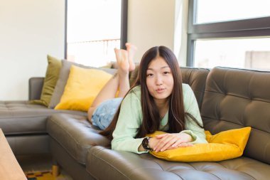 Genç Asyalı bir kadın tatlı, eğlenceli, mutlu, sevimli bir ifadeyle dudaklarını birbirine bastırıyor. Öpücük yolluyor.