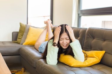 Asyalı genç bir kadın stresli ve hayal kırıklığına uğramış hissediyor. Eli kolu bağlı, yorgun, mutsuz ve migren ağrısı çekiyor.