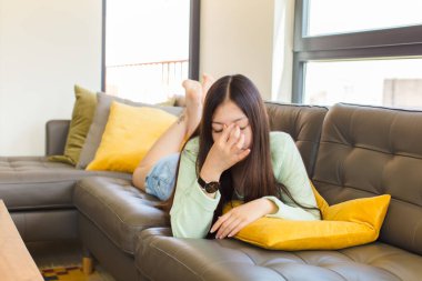 Genç Asyalı kadın stresli, mutsuz ve hayal kırıklığına uğramış, alınına dokunmuş ve şiddetli baş ağrısı çeken.