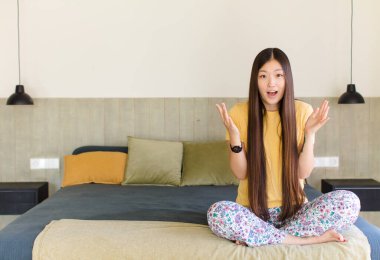 Genç Asyalı kadın şok olmuş ve şaşırmış, endişeli ve paniklemiş, stresli ve dehşete kapılmış bir bakışla