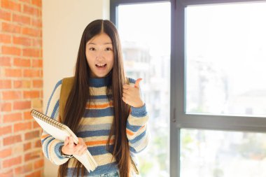 Genç Asyalı kadın kendini mutlu, şaşkın, tatmin olmuş ve şaşırmış hissediyor, tamam gösteriyor ve el kol hareketleri yapıyor, gülümsüyor.