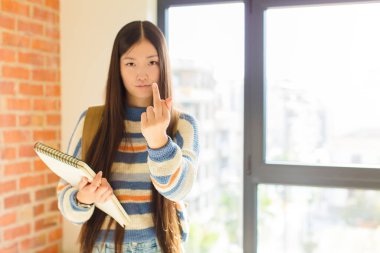 Asyalı genç bir kadın kızgın, sinirli, asi ve agresif hissediyor, orta parmağını sallıyor, karşı koyuyor.