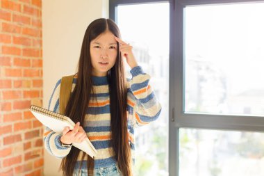 Genç Asyalı kadın şaşkın ve şaşkın hissediyor. Deli, deli ya da aklını kaçırmış olduğunu gösteriyor.