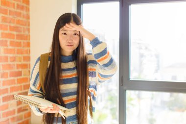 Genç Asyalı kadın şaşkınlık ve şaşkınlık içinde bakıyor, el üstünde, uzaklara bakıyor, izliyor ya da arıyor.