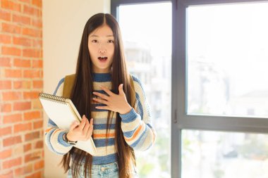 Genç Asyalı kadın şaşkın, şaşkın ve şaşırmış hissediyor, elleri göğsünde ve ağzı açık, kim olduğunu söylüyor, ben?