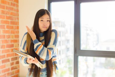 Genç Asyalı kadın kafası karışık ve bilgisiz, şüpheli bir açıklama ya da düşünceyi merak ediyor.