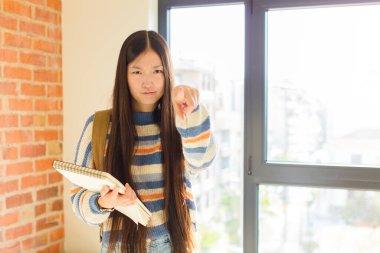 Genç Asyalı kadın kameraya hem parmaklarıyla hem de kızgın bir ifadeyle sana görevini yapmanı söylüyor.
