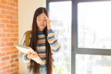 Asyalı genç bir kadın stresli ve hayal kırıklığına uğramış görünüyor. Baskı altında, baş ağrısı ve sorunlarıyla çalışıyor.