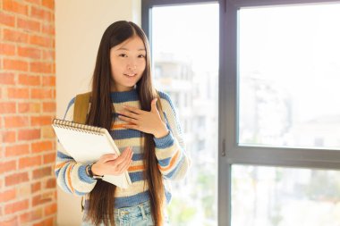 Genç Asyalı kadın romantik, mutlu ve aşık, neşeyle gülümseyen ve kalbe yakın el ele tutuşan