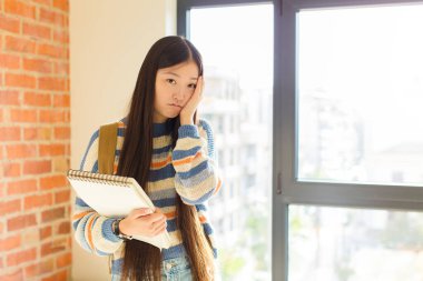 Genç Asyalı kadın yorgun, sıkıcı ve can sıkıcı bir görevden sonra sıkılmış, hayal kırıklığına uğramış ve uykulu hissediyor.