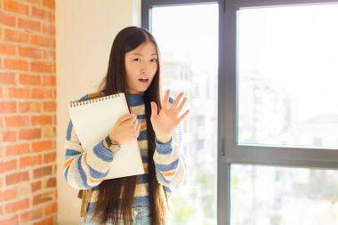 Genç Asyalı kadın korku ve panik içinde geri çekilip çığlık atıyor ve bir kabusa tepki veriyor.