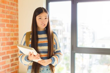 Asyalı genç bir kadın hangi seçeneği seçeceğine karar veremediği için bilgisiz, kafası karışık ve kararsız hissediyor.