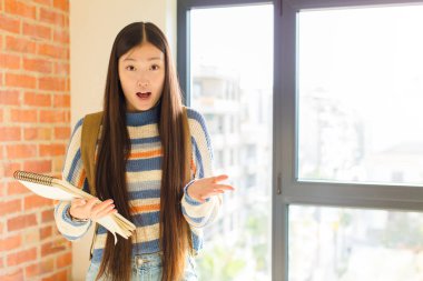 Genç Asyalı kadın şok olmuş ve şaşırmış, endişeli ve paniklemiş, stresli ve dehşete kapılmış bir bakışla