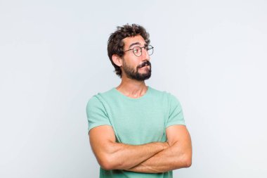 Genç sakallı adam şüphe ediyor ya da düşünüyor, dudağını ısırıyor ve kendini güvensiz ve gergin hissediyor, kenarda yer arıyor.